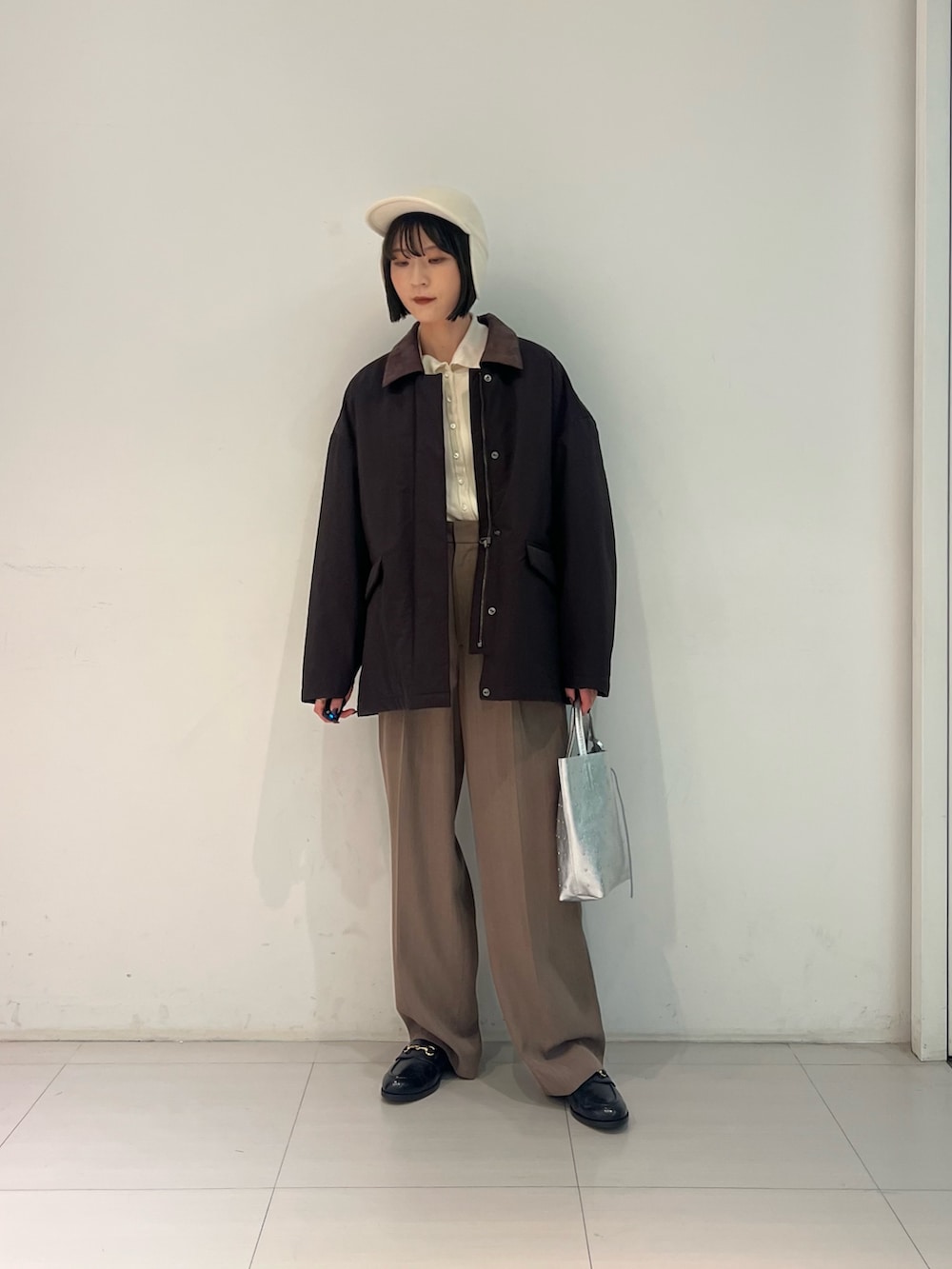 ブラック系のローファー、シルバー系のトートバッグ、ブラウン系のダウンジャケット/コートを着用したレディースの秋コーディネートの2枚目の写真