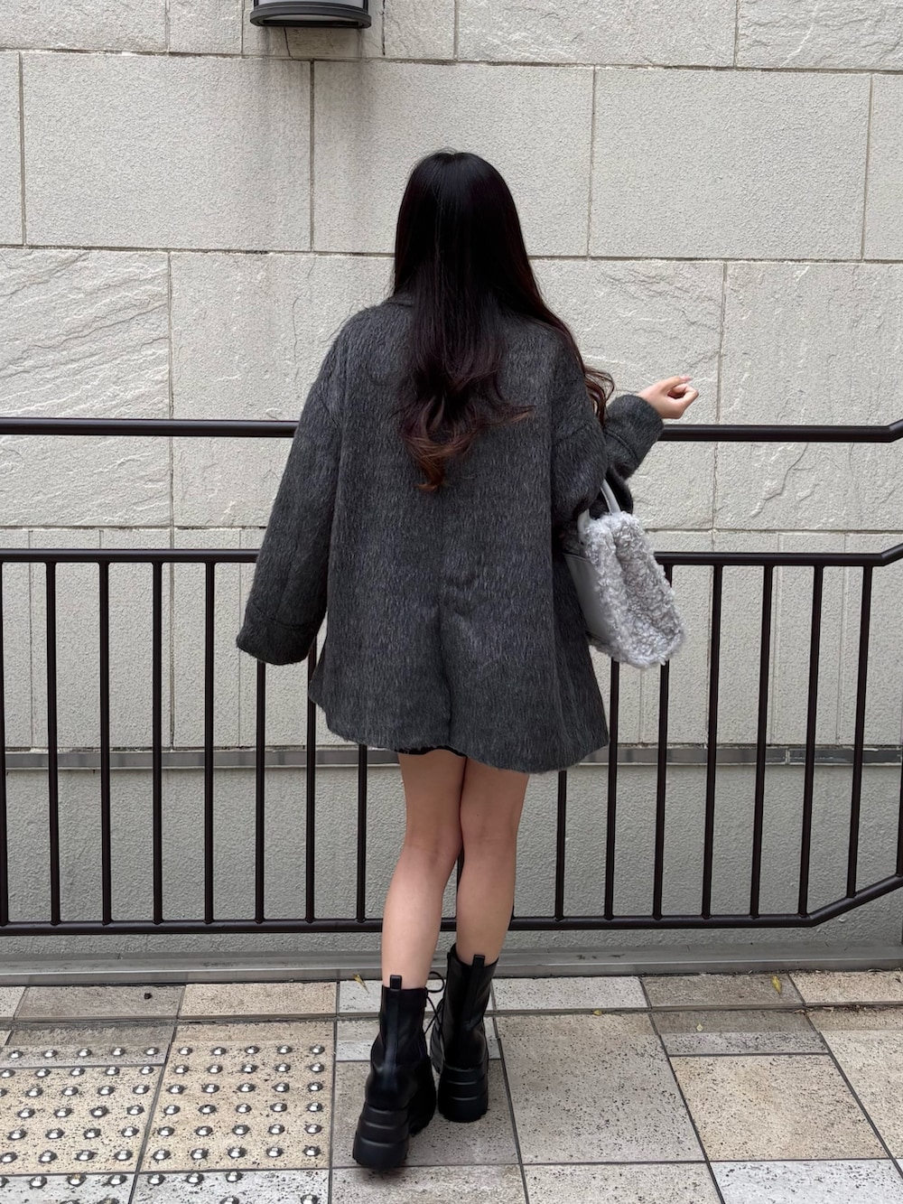 ブラック系のワンピース、グレー系のその他アウター、ブラック系のブーツを着用したレディースの秋コーディネートの2枚目の写真