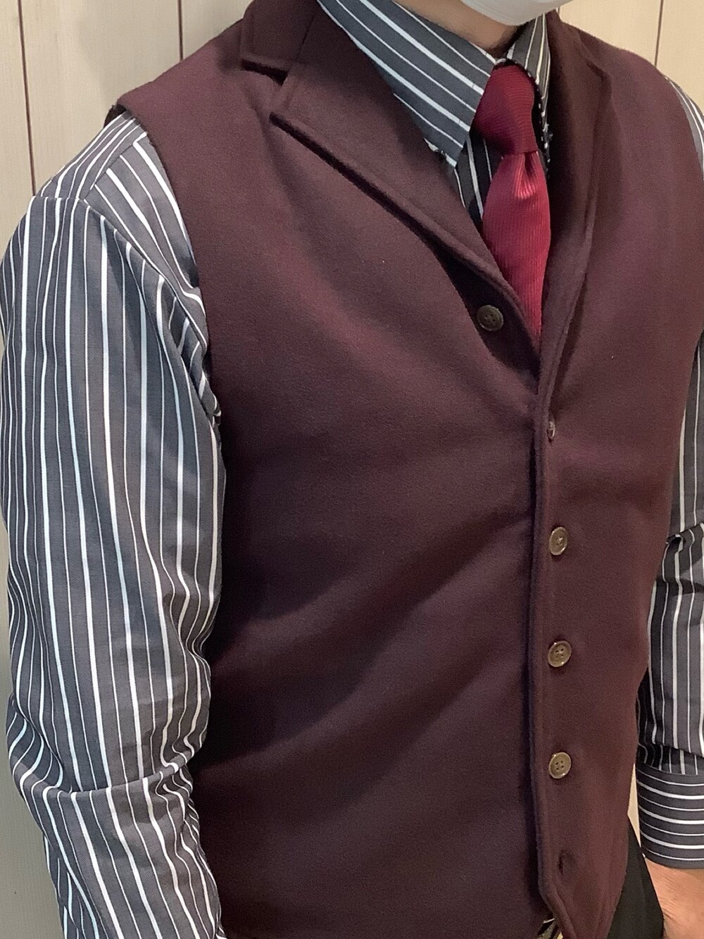 レッド系のネクタイ、ブラック系のビジネスシャツ、レッド系のベストを着用したメンズの冬コーディネートの3枚目の写真