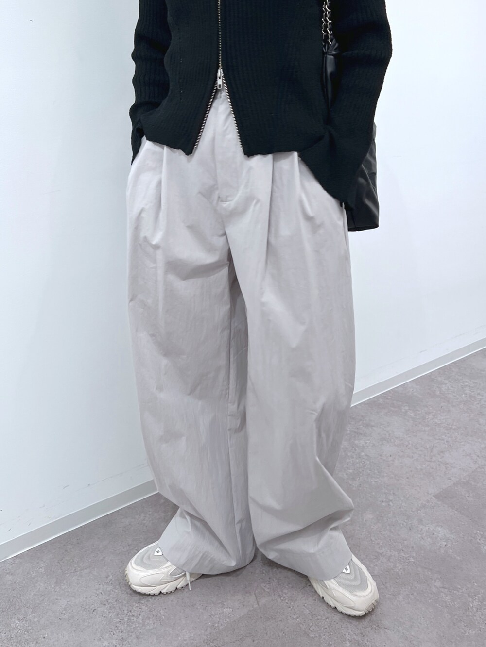 ブラック系のニット/セーター、グレー系のスラックス、ブラック系のトートバッグを着用したレディースの春コーディネートの4枚目の写真