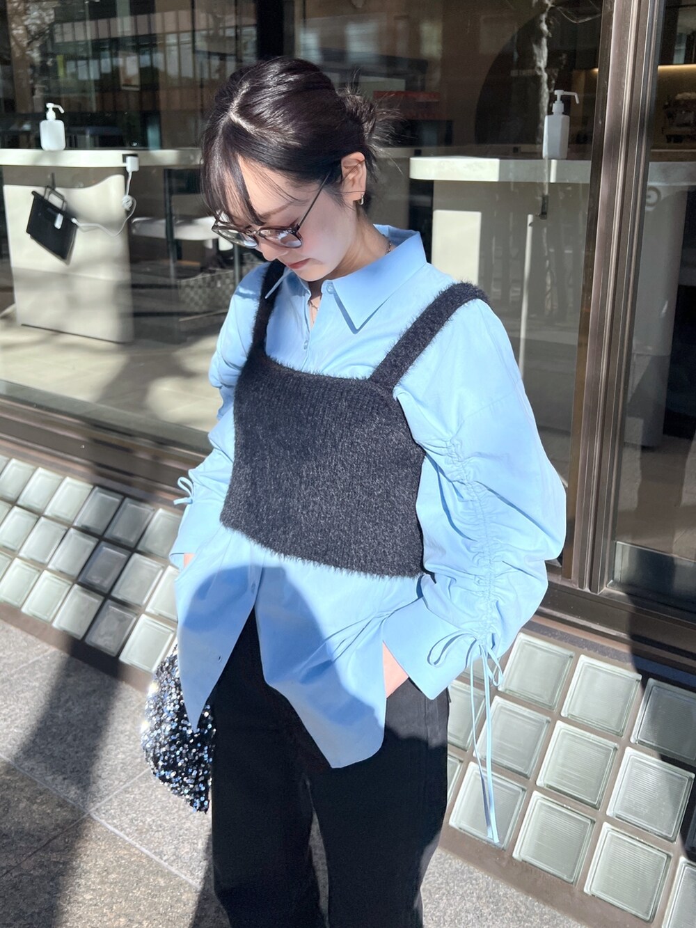 ブラック系のベスト、ブルー系のシャツ/ブラウス、ブラック系のハンドバッグを着用したレディースの冬コーディネートの2枚目の写真