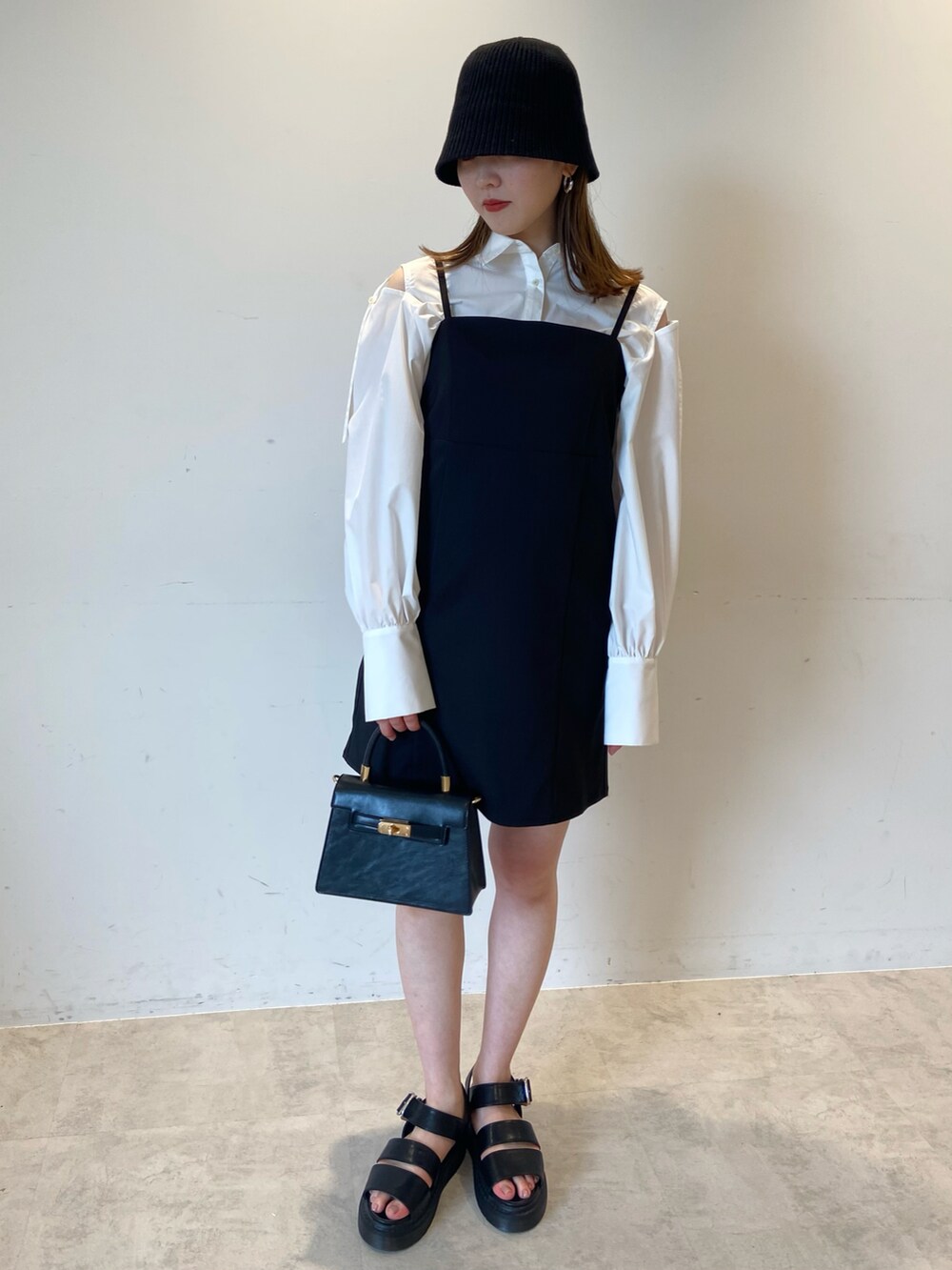 ブラック系のハンドバッグ、ホワイト系のシャツ/ブラウス、ブラック系のサンダルを着用したレディースの夏コーディネートの2枚目の写真