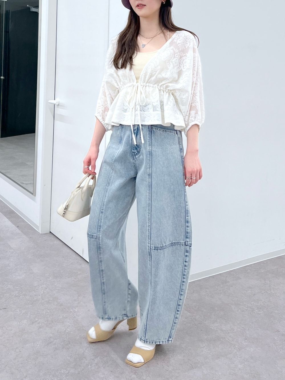 ブルー系のデニムパンツ、ホワイト系のカーディガン/ボレロ、ベージュ系のサンダルを着用したレディースの春コーディネートの2枚目の写真