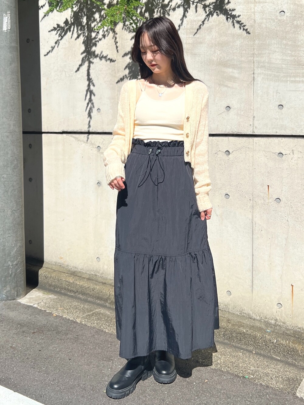 ホワイト系のカーディガン/ボレロ、ブラック系のスカートを着用したレディースの秋コーディネートの2枚目の写真