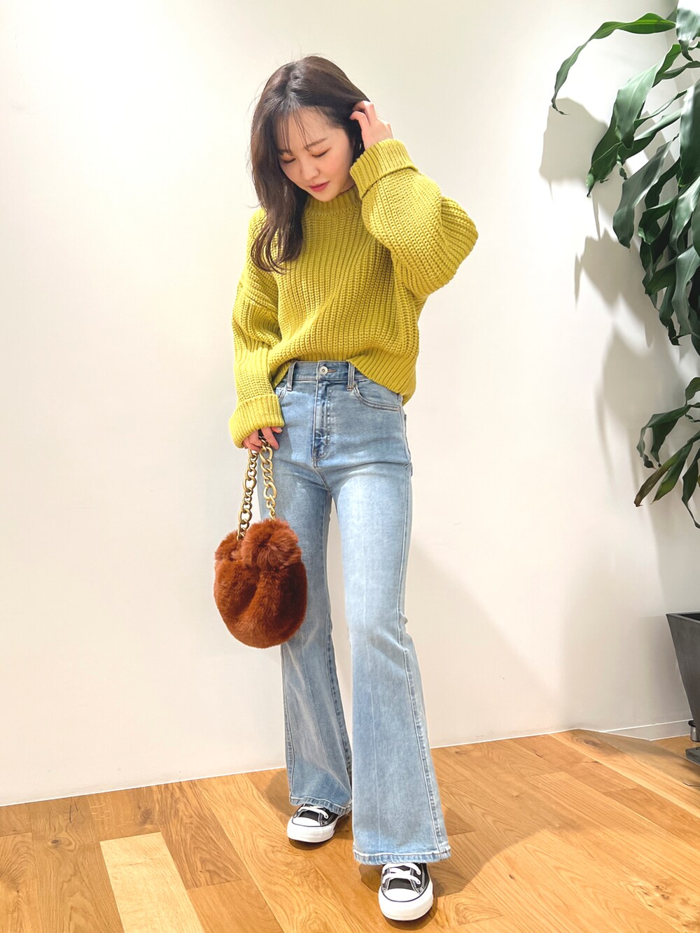 イエロー系のニット/セーター、ブルー系のデニムパンツ、ブラウン系のハンドバッグを着用したレディースの秋コーディネートの2枚目の写真