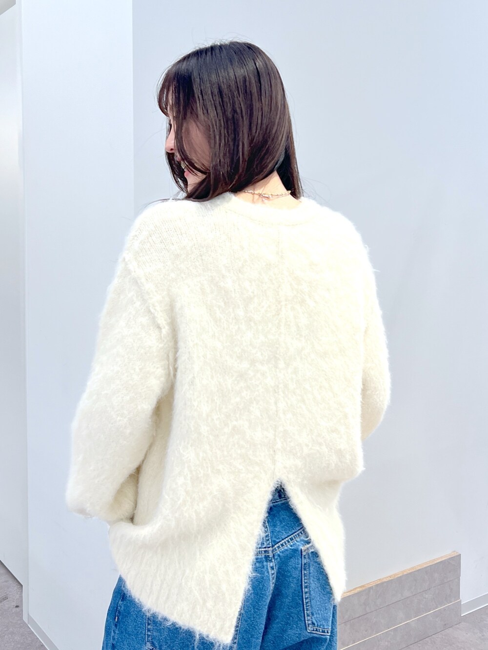 ホワイト系のニット/セーター、ブルー系のデニムパンツを着用したレディースの冬コーディネートの3枚目の写真