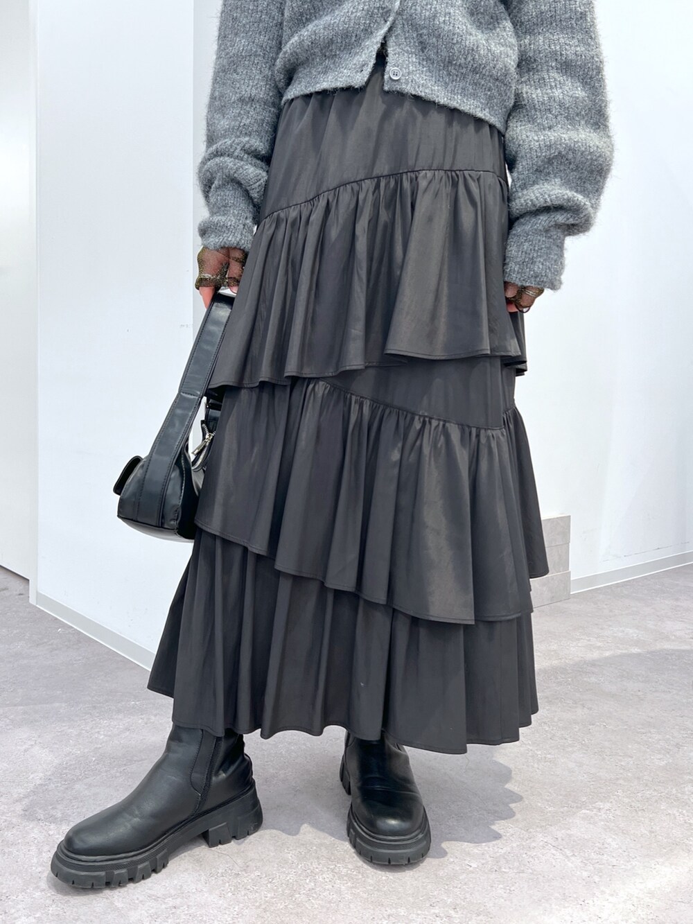 グレー系のニット/セーター、ブラック系のスカート、ブラック系のTシャツ/カットソーを着用したレディースの冬コーディネートの3枚目の写真