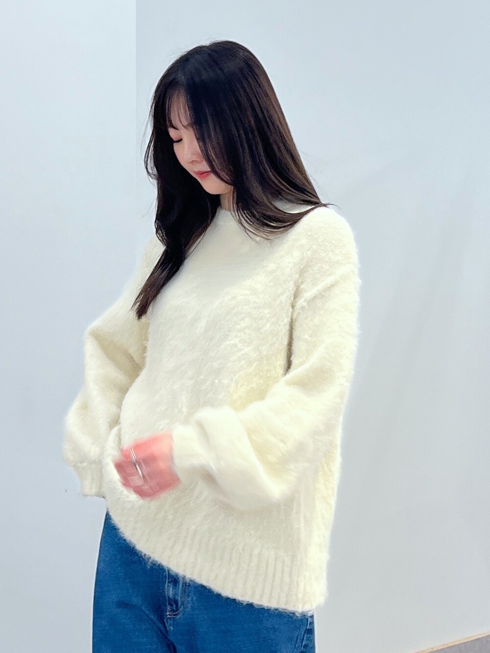 ホワイト系のニット/セーター、ブルー系のデニムパンツを着用したレディースの冬コーディネートの2枚目の写真