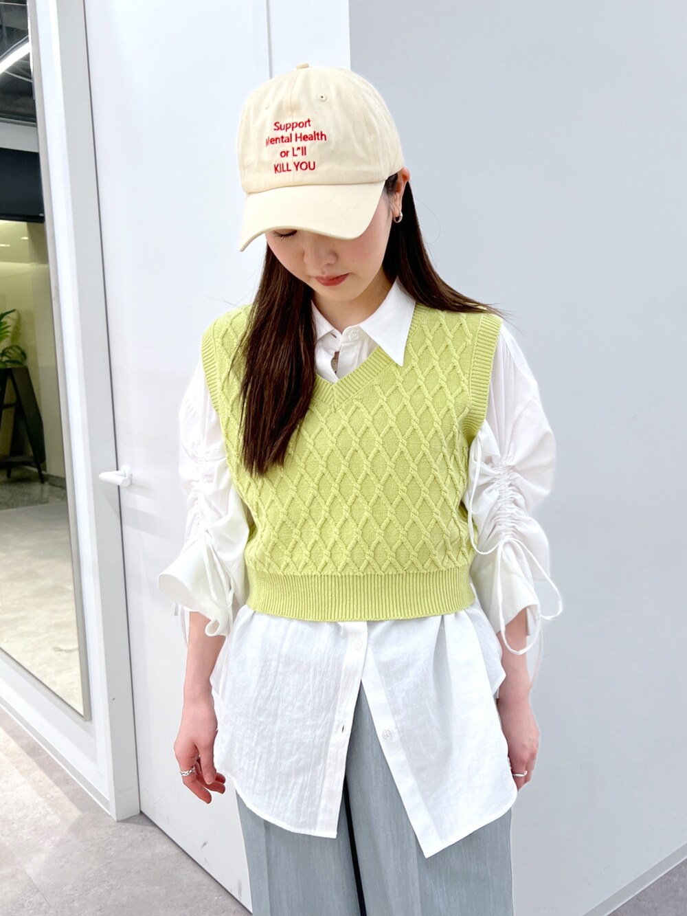 グリーン系のベスト、ホワイト系のシャツ/ブラウス、グレー系のスラックスを着用したレディースの春コーディネートの2枚目の写真