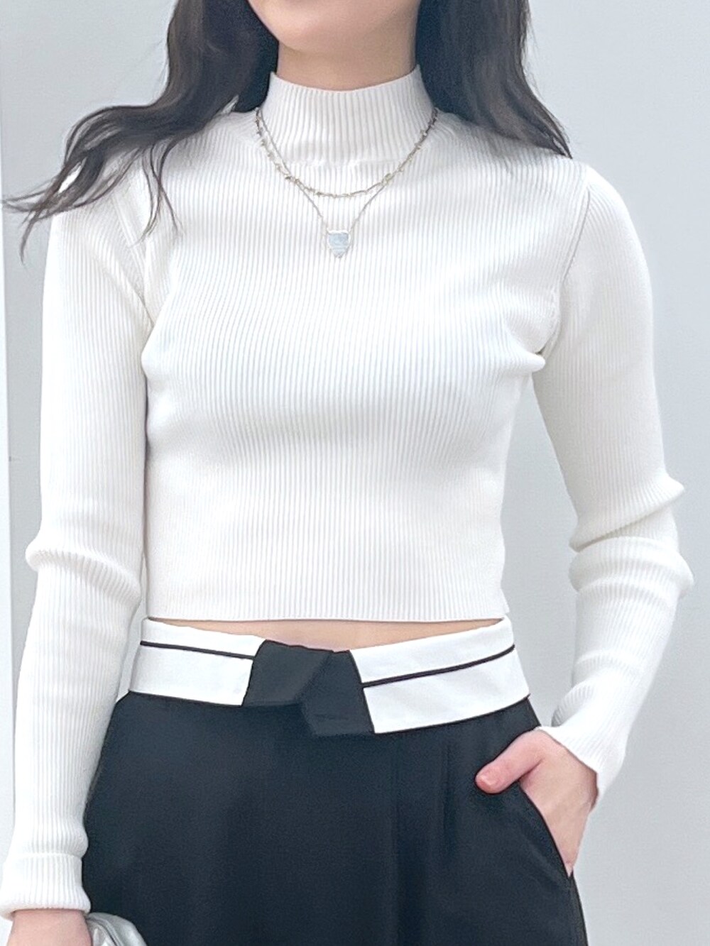 ホワイト系のニット/セーター、ブラック系のスラックス、シルバー系のショルダーバッグを着用したレディースの冬コーディネートの2枚目の写真