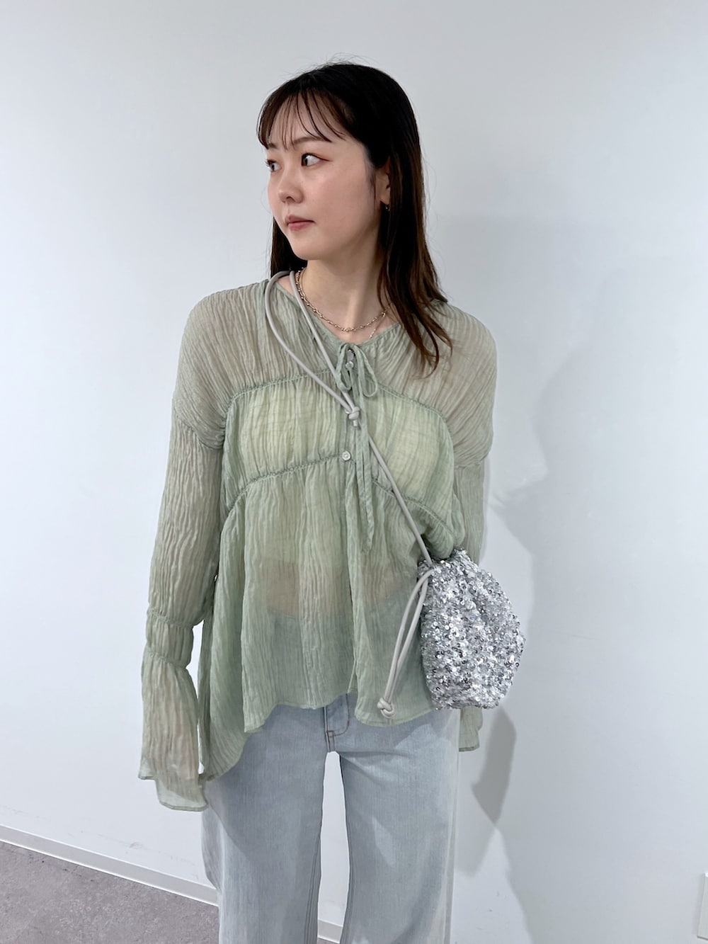 グリーン系のシャツ/ブラウス、シルバー系のバレエシューズ、シルバー系のハンドバッグを着用したレディースの春コーディネートの2枚目の写真