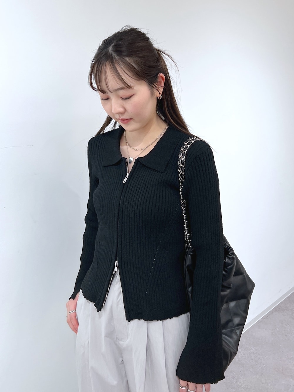 ブラック系のニット/セーター、グレー系のスラックス、ブラック系のトートバッグを着用したレディースの春コーディネートの2枚目の写真