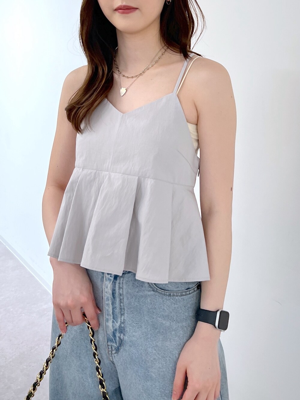 ブルー系のデニムパンツ、ブラック系のトートバッグ、グレー系のベストを着用したレディースの夏コーディネートの2枚目の写真