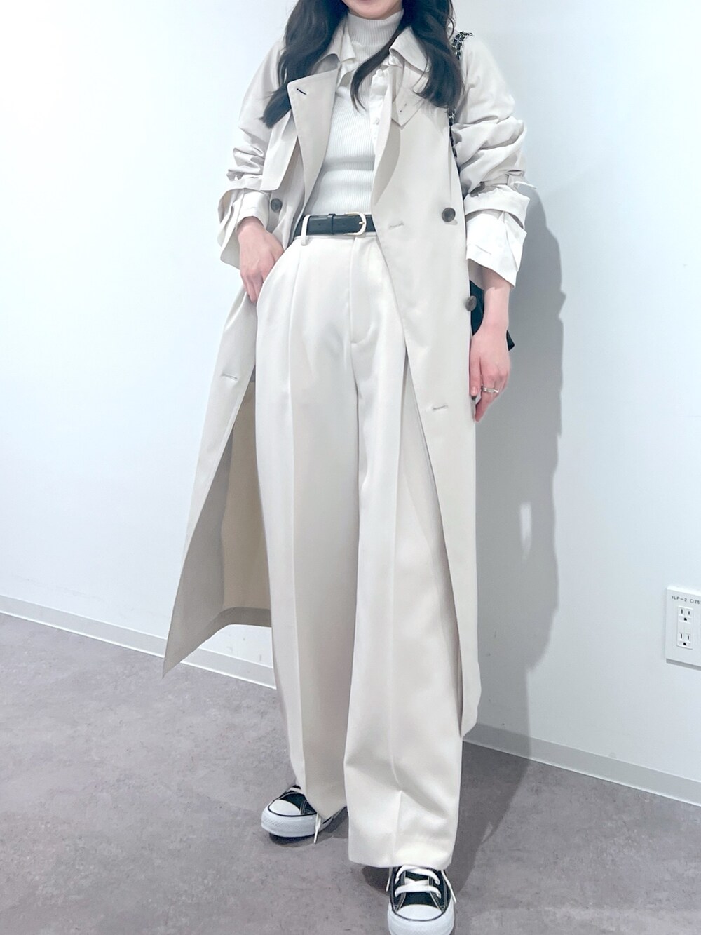 ホワイト系のスラックス、ホワイト系のトレンチコート、ブラック系のトートバッグを着用したレディースの冬コーディネートの2枚目の写真