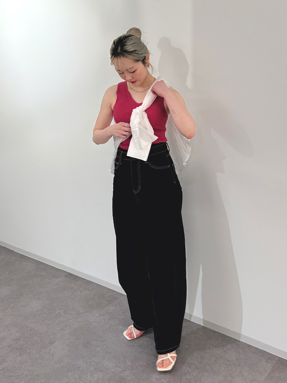 ブルー系のデニムパンツ、ピンク系のタンクトップ、ホワイト系のサンダルを着用したレディースの春コーディネートの2枚目の写真