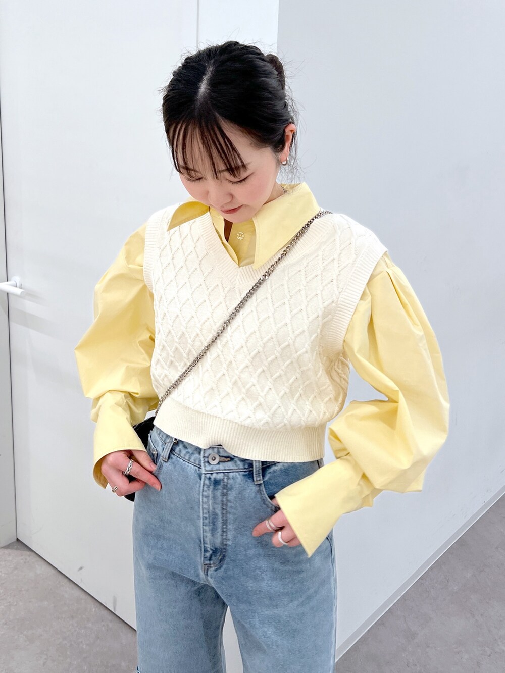 ホワイト系のベスト、イエロー系のシャツ/ブラウス、ブルー系のデニムパンツを着用したレディースの春コーディネートの2枚目の写真