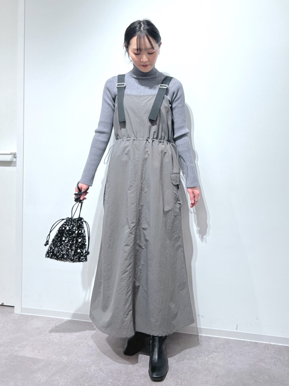 グレー系のニット/セーター、グレー系のワンピース、ブラック系のハンドバッグを着用したレディースの冬コーディネートの2枚目の写真