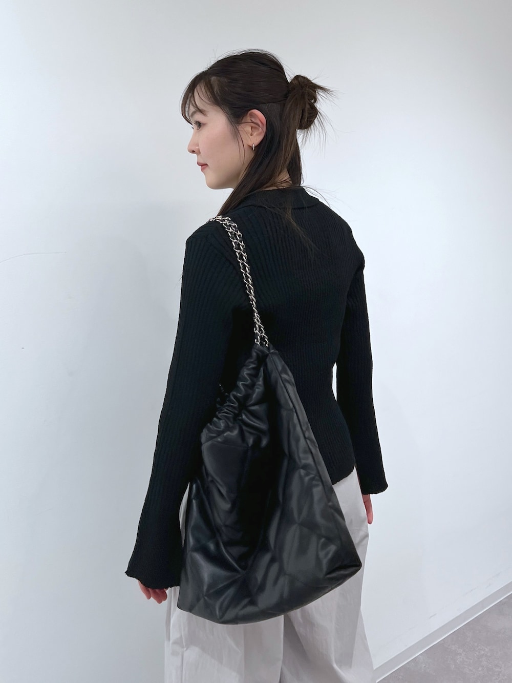 ブラック系のニット/セーター、グレー系のスラックス、ブラック系のトートバッグを着用したレディースの春コーディネートの3枚目の写真