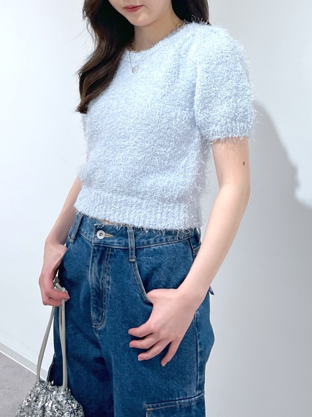 ブルー系のニット/セーター、ブルー系のデニムパンツ、シルバー系のハンドバッグを着用したレディースの春コーディネートの2枚目の写真