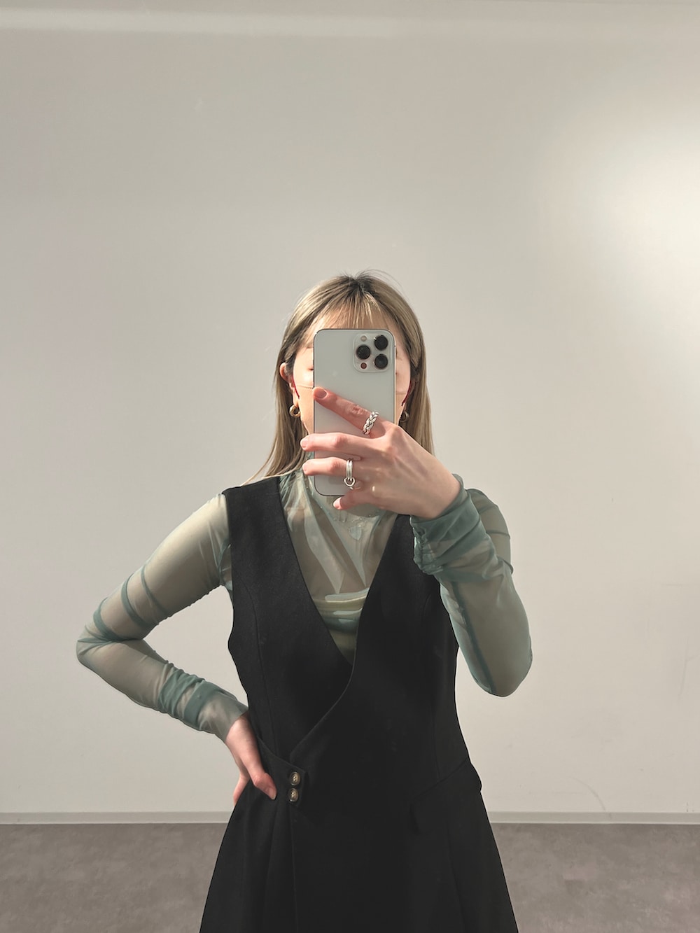 ブラック系のジャンパースカート、グリーン系のTシャツ/カットソーを着用したレディースの冬コーディネートの2枚目の写真