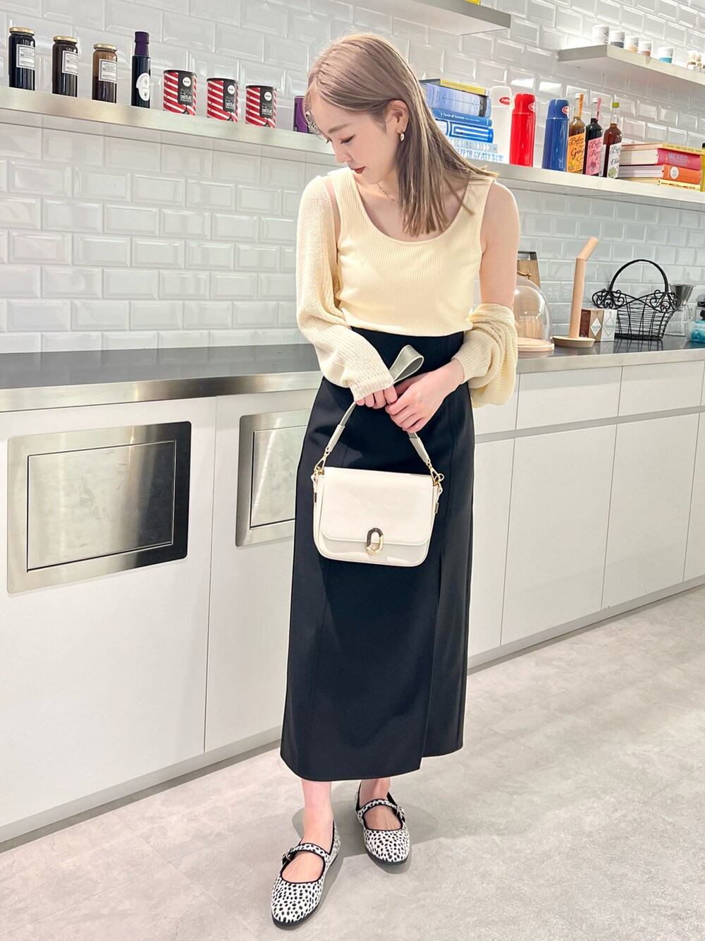 ホワイト系のカーディガン/ボレロ、ブラック系のスカート、ホワイト系のショルダーバッグを着用したレディースの夏コーディネートの2枚目の写真