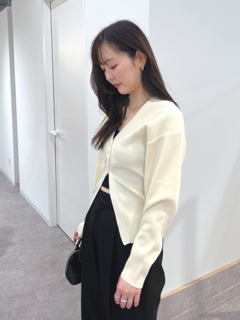 ホワイト系のカーディガン/ボレロ、ブラック系のスラックス、ブラック系のショルダーバッグを着用したレディースの冬コーディネートの2枚目の写真