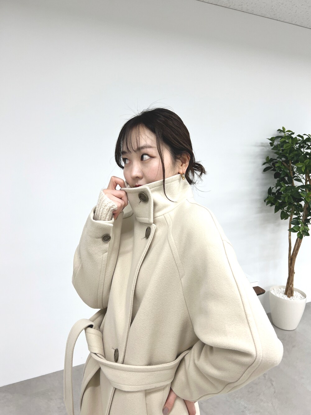 ベージュ系のステンカラーコート、ホワイト系のニット/セーター、ベージュ系のスラックスを着用したレディースの秋コーディネートの3枚目の写真
