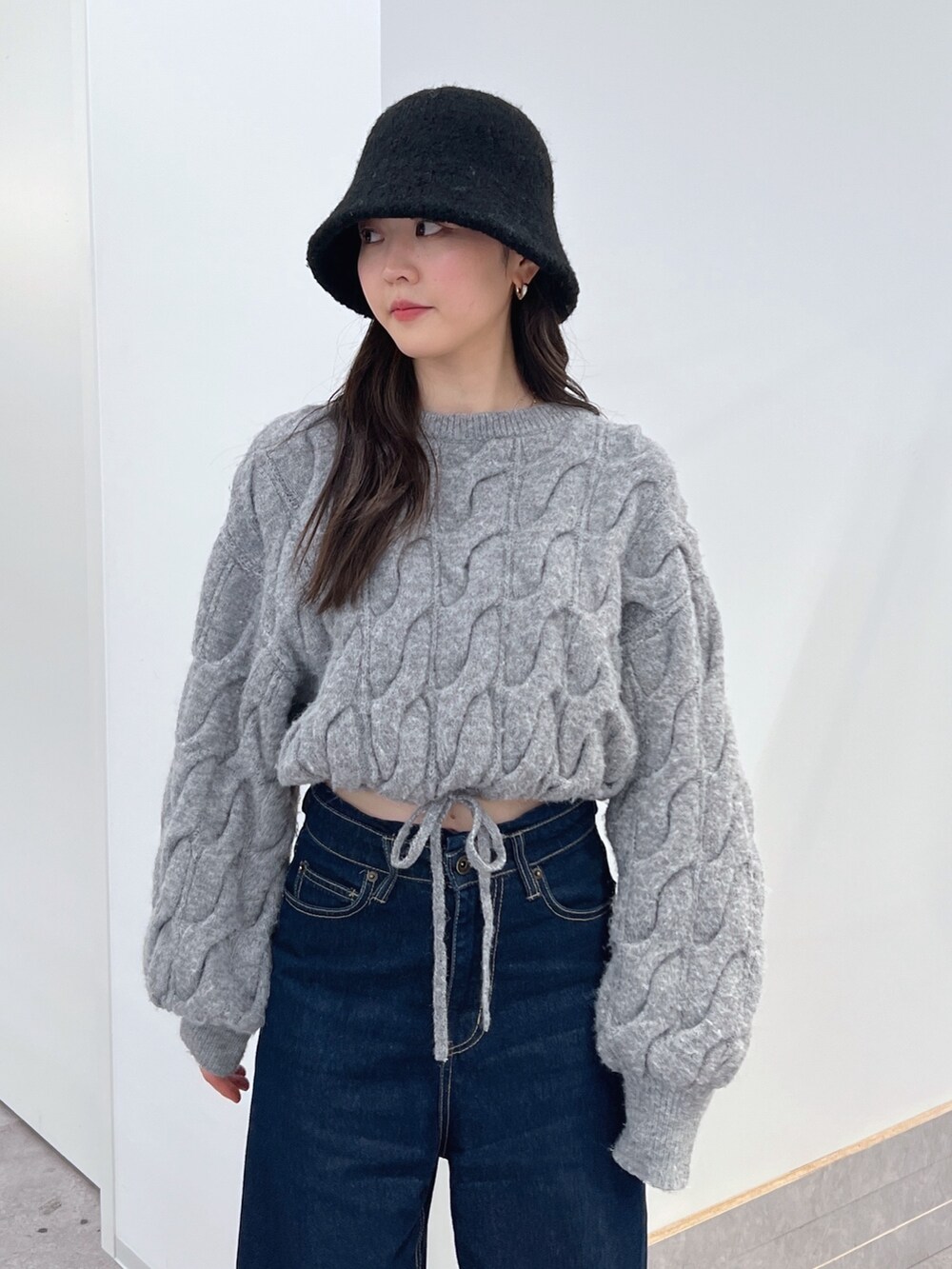 グレー系のニット/セーター、ブルー系のデニムパンツ、ブラック系のブーツを着用したレディースの冬コーディネートの2枚目の写真