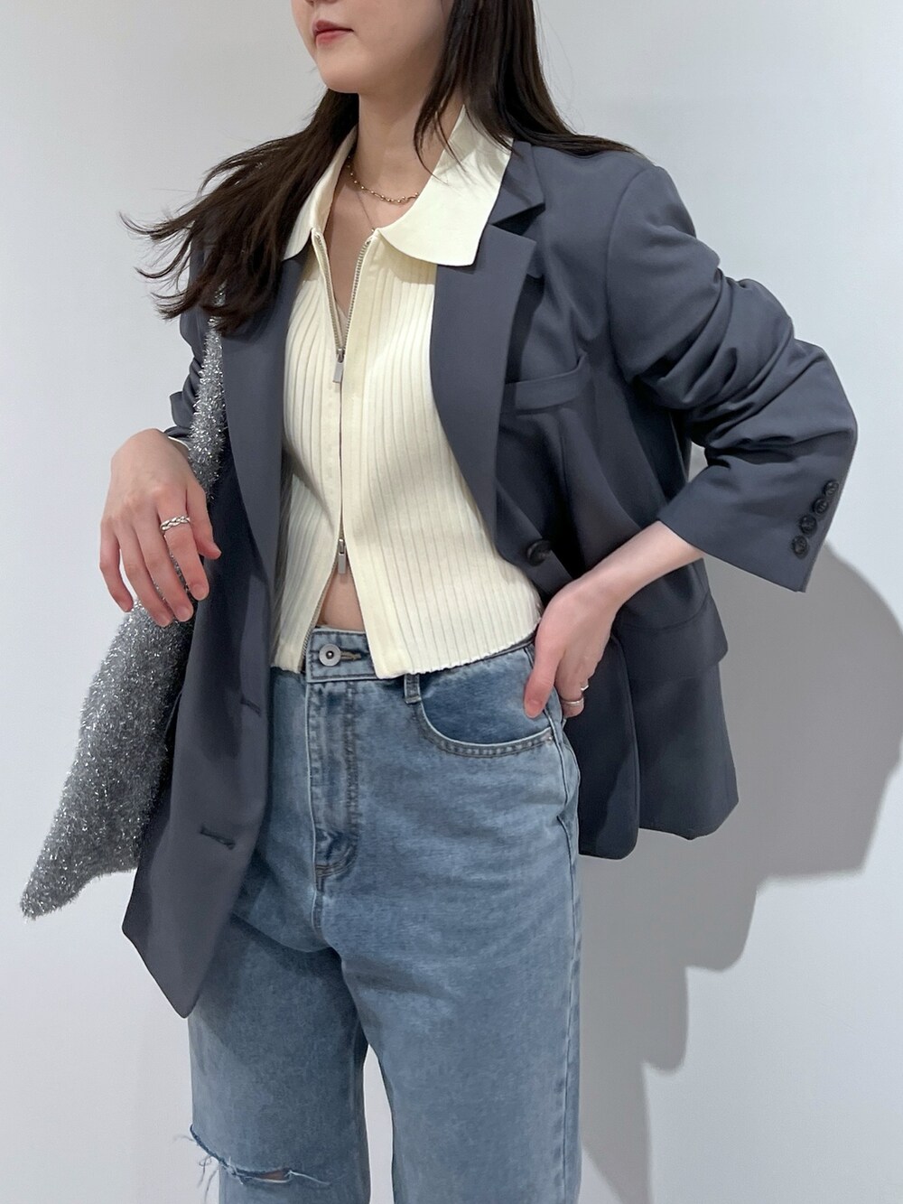 ブルー系のデニムパンツ、グレー系のテーラードジャケット、ホワイト系のニット/セーターを着用したレディースの春コーディネートの2枚目の写真