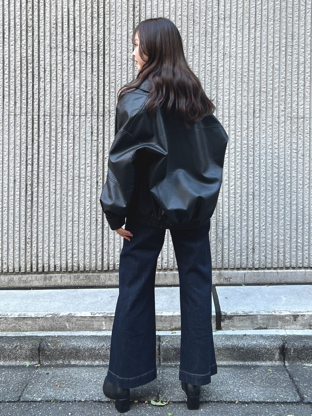 ブラック系のライダースジャケット、ブルー系のデニムパンツ、ブラック系のブーツを着用したレディースの秋コーディネートの2枚目の写真