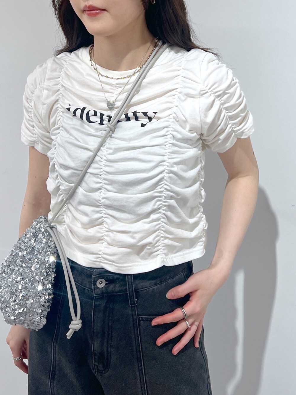 ブラック系のデニムパンツ、シルバー系のハンドバッグ、ホワイト系のTシャツ/カットソーを着用したレディースの春コーディネートの2枚目の写真