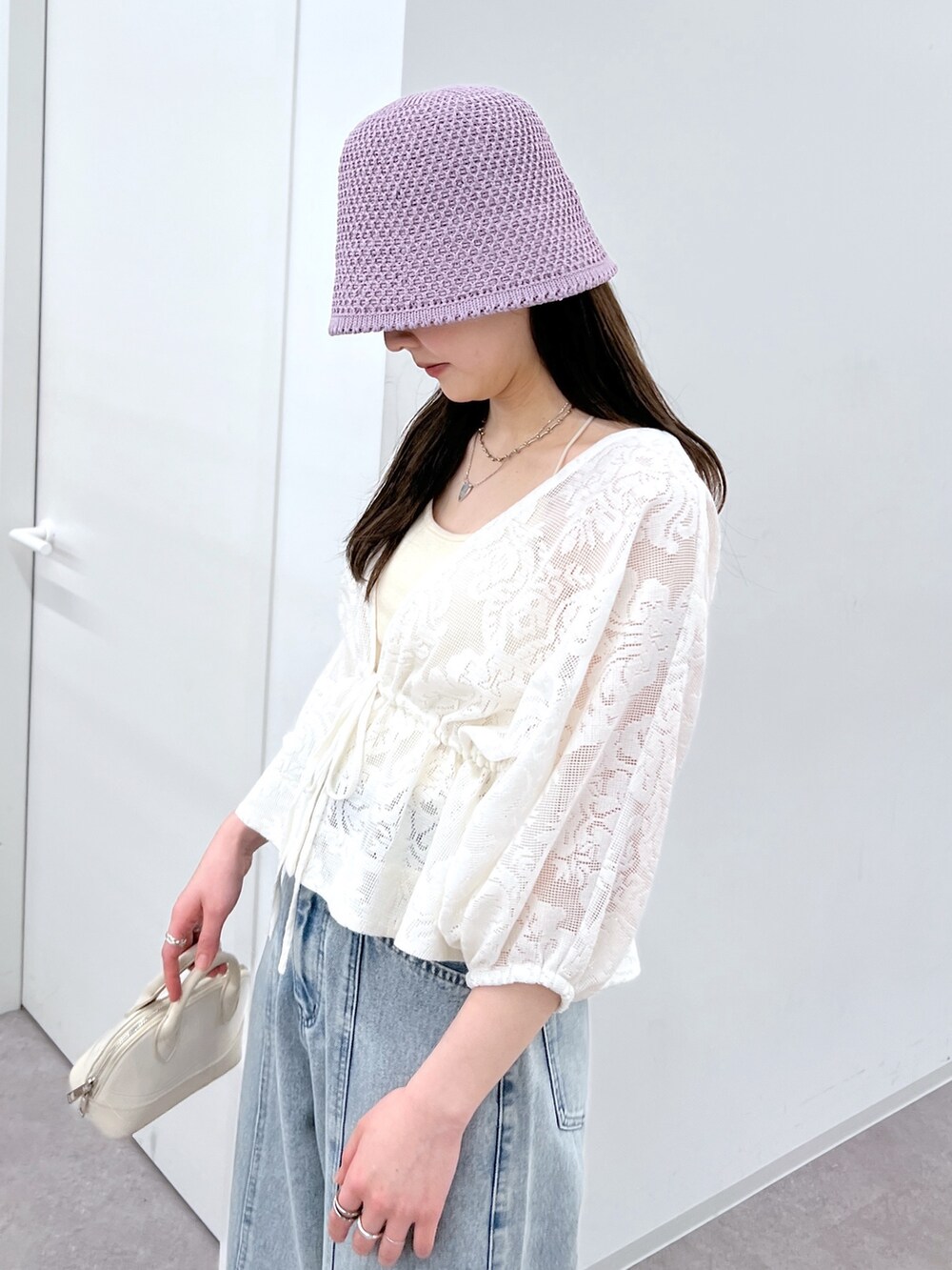 ブルー系のデニムパンツ、ホワイト系のカーディガン/ボレロ、ベージュ系のサンダルを着用したレディースの春コーディネートの3枚目の写真