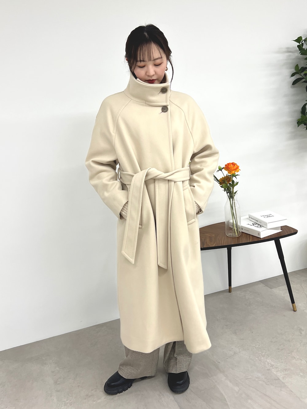 ベージュ系のステンカラーコート、ホワイト系のニット/セーター、ベージュ系のスラックスを着用したレディースの秋コーディネートの2枚目の写真
