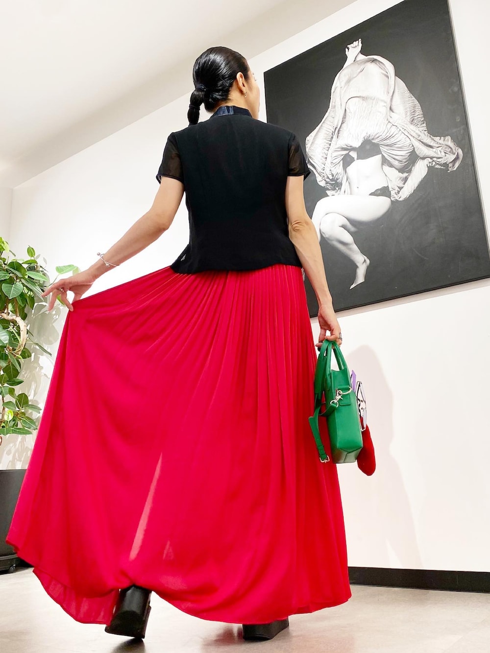 ピンク系のスカート、グリーン系のショルダーバッグ、ブラック系のサンダルを着用したレディースの夏コーディネートの2枚目の写真