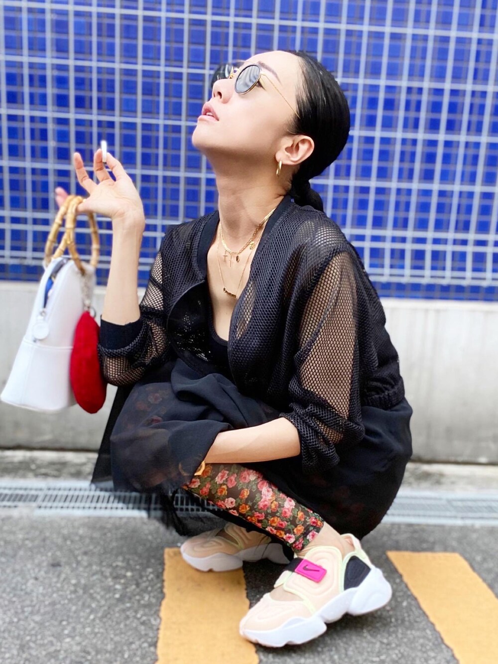 ホワイト系のバッグ、ブラック系のブルゾン、ブラック系のタンクトップを着用したレディースの夏コーディネートの4枚目の写真