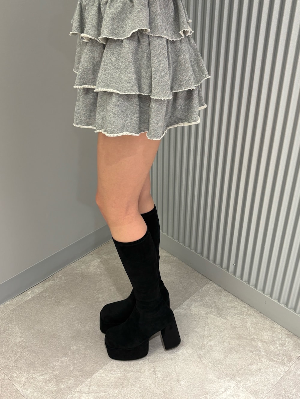 グレー系のスカート、ブラック系のニット/セーター、ブラック系のブーツを着用したレディースの秋コーディネートの8枚目の写真