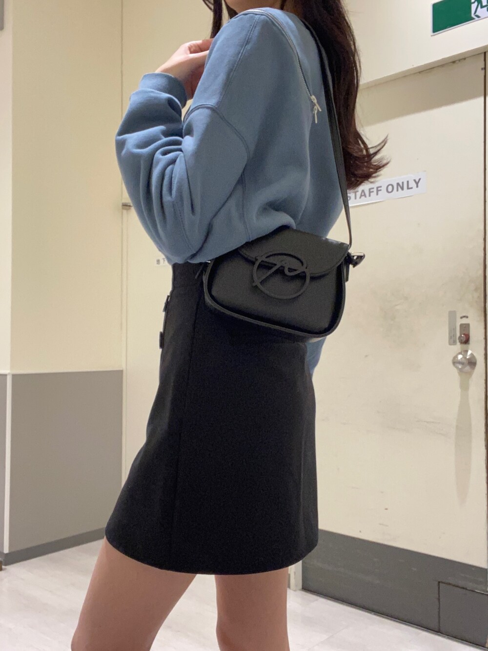 ブラック系のスカート、ブルー系のTシャツ/カットソー、ブラック系のショルダーバッグを着用したレディースの秋コーディネートの6枚目の写真