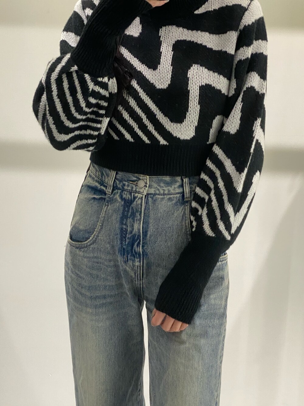 ブルー系のデニムパンツ、ブラック系のニット/セーター、ブラック系のブーツを着用したレディースの冬コーディネートの2枚目の写真