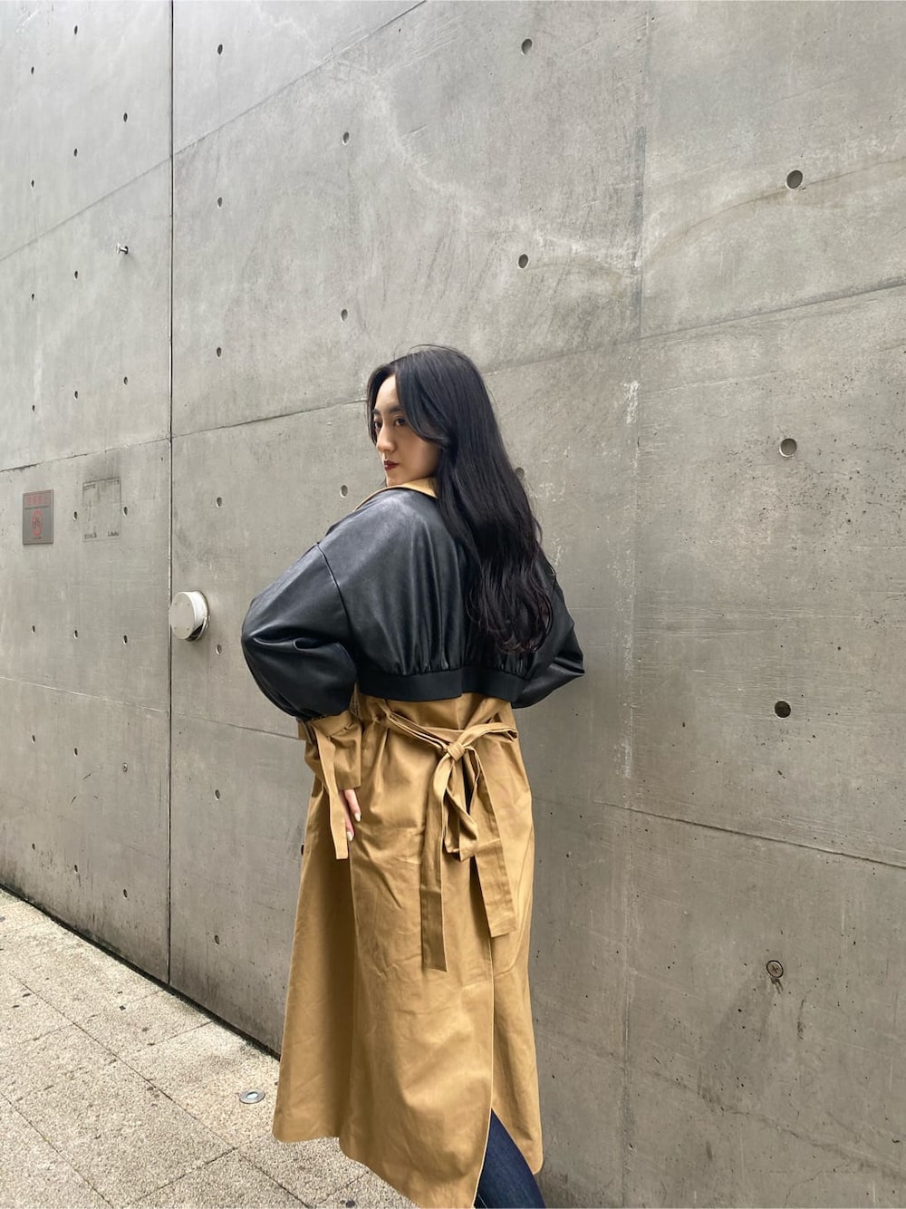 ブルー系のデニムパンツ、ベージュ系のトレンチコート、ブラック系のニット/セーターを着用したレディースの秋コーディネートの3枚目の写真