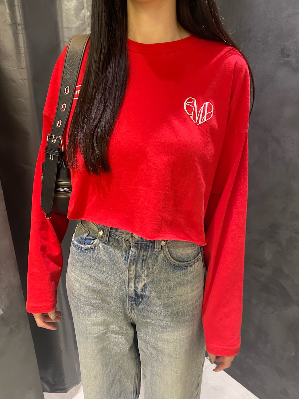 ブルー系のデニムパンツ、ブラック系のハンドバッグ、レッド系のTシャツ/カットソーを着用したレディースの秋コーディネートの6枚目の写真