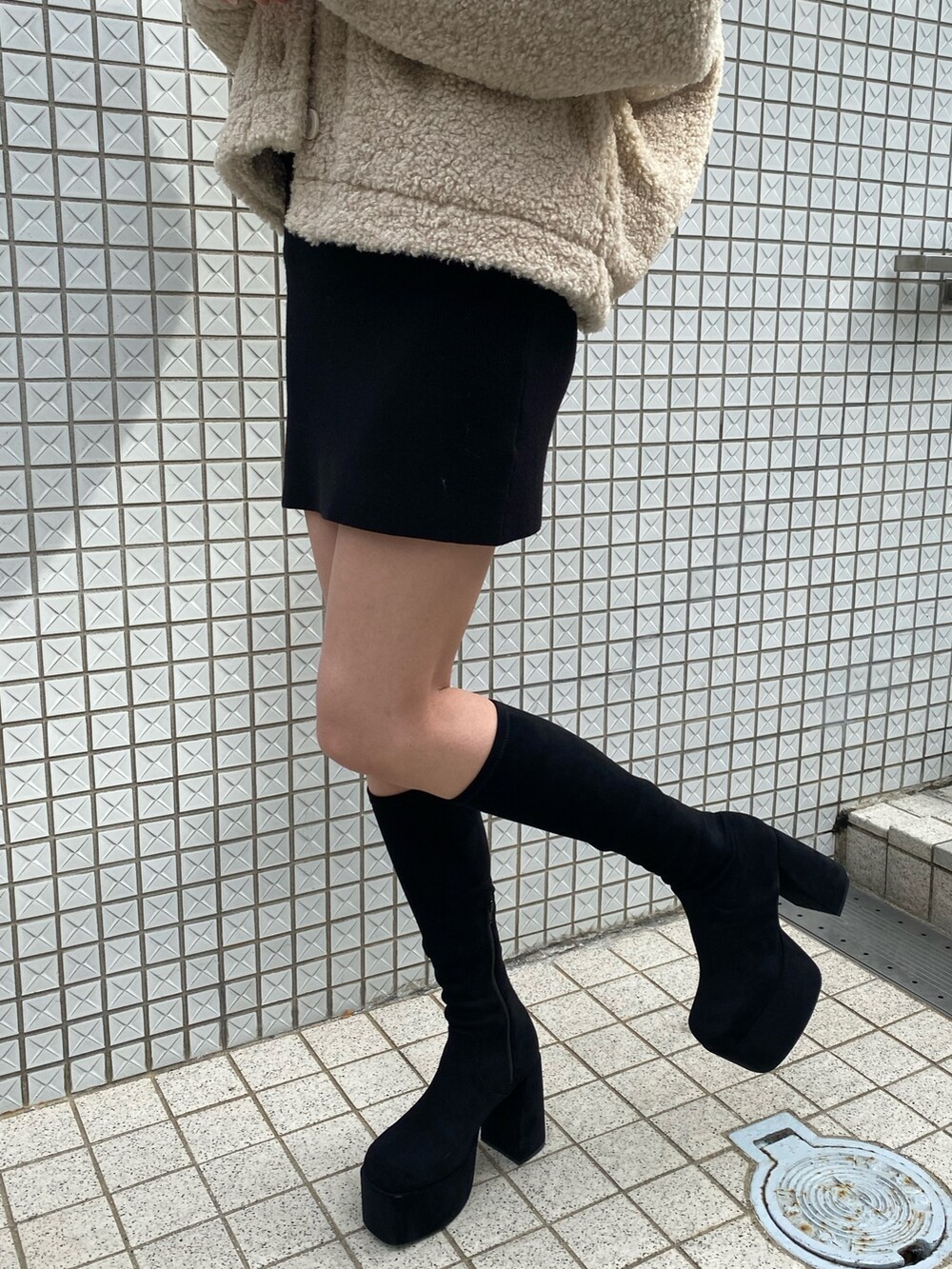 ブラック系のワンピース、ホワイト系のブルゾン、ブラック系のブーツを着用したレディースの冬コーディネートの9枚目の写真
