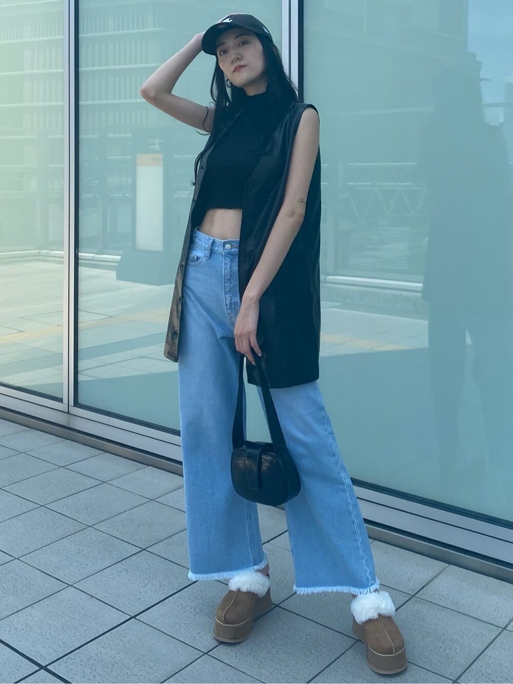 ブルー系のデニムパンツ、ブラック系のワンピース、ベージュ系のスリッポンを着用したレディースの夏コーディネートの3枚目の写真