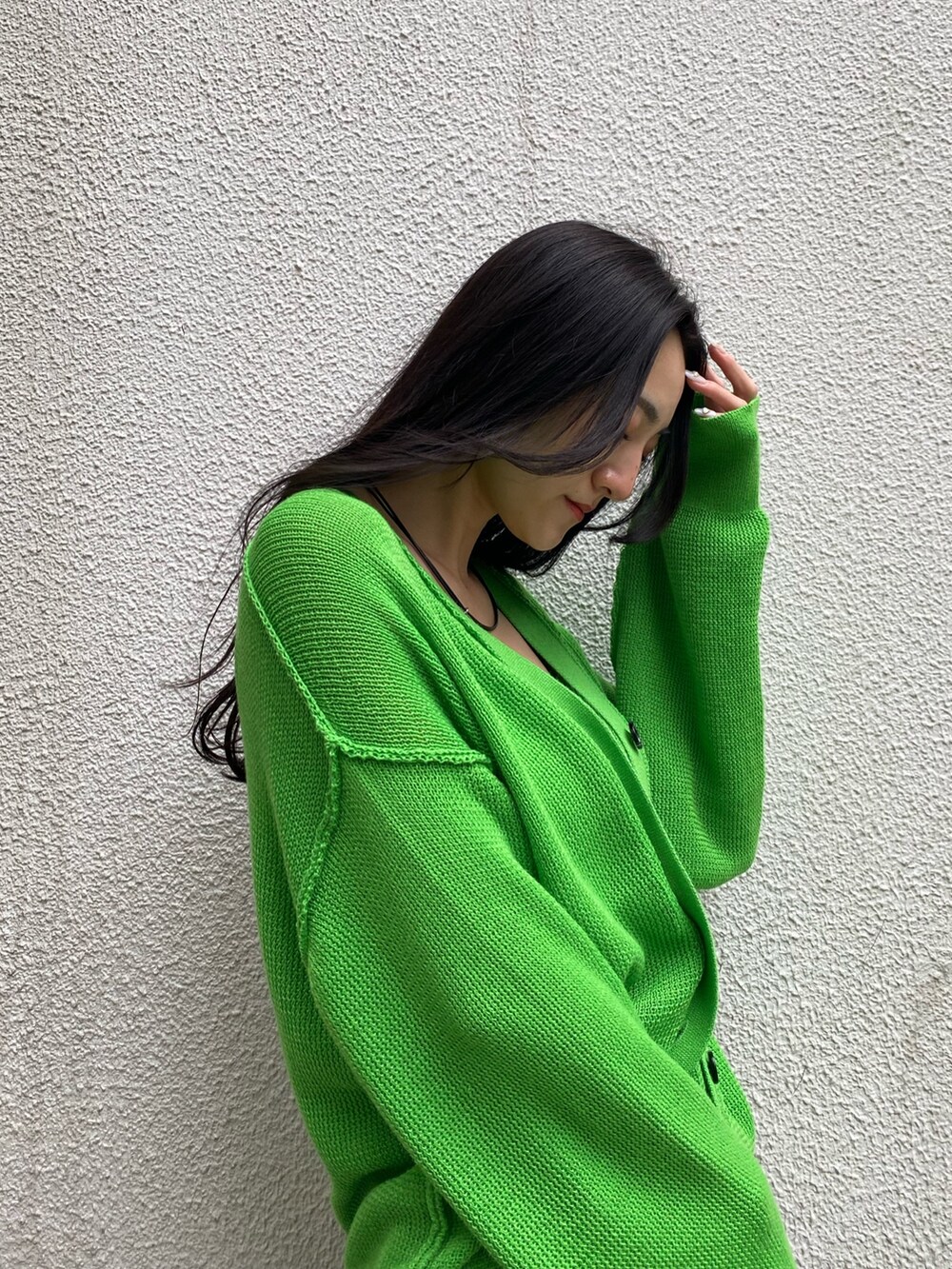 グリーン系のカーディガン/ボレロ、ホワイト系のキャミソール、ブラック系のデニムパンツを着用したレディースの春コーディネートの6枚目の写真