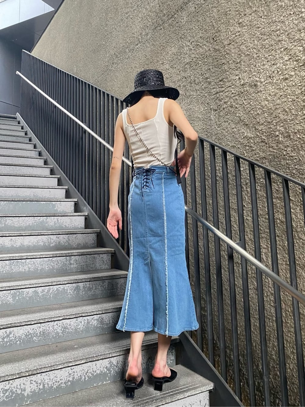 ブルー系のスカート、ホワイト系のタンクトップ、ブラック系のサンダルを着用したレディースの夏コーディネートの3枚目の写真