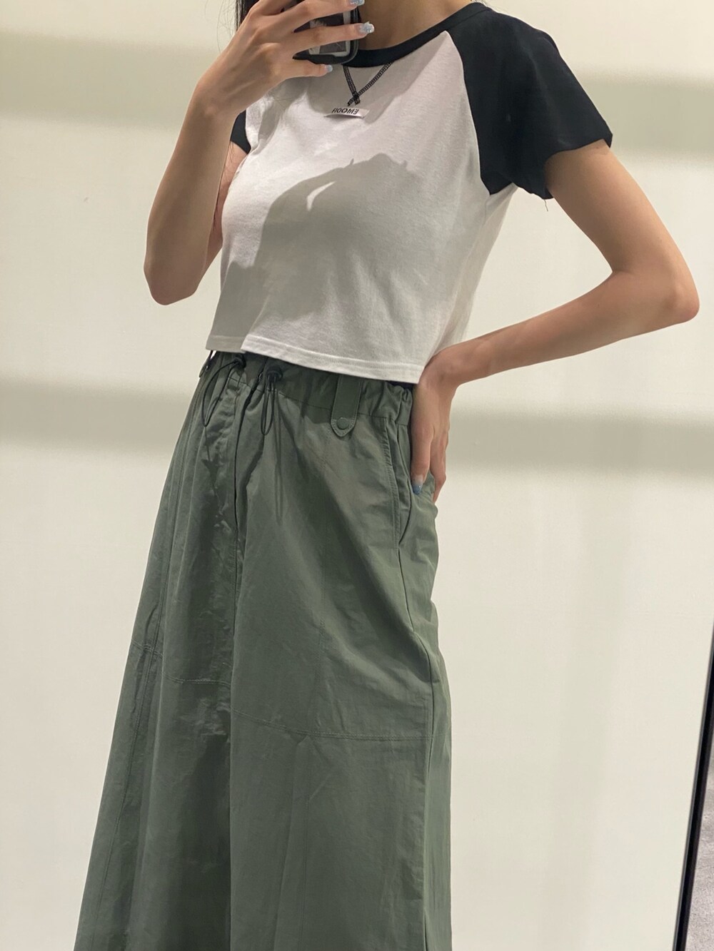 グリーン系のスカート、ブラック系のTシャツ/カットソー、ブラック系のサンダルを着用したレディースの夏コーディネートの6枚目の写真