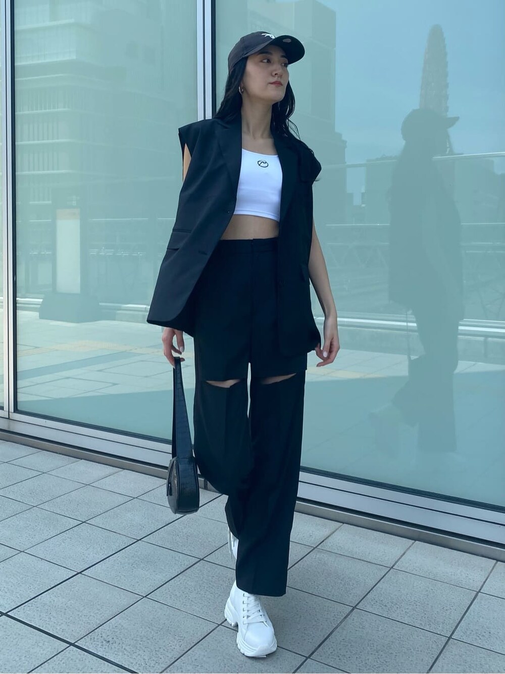 ホワイト系のスニーカー、ブラック系のベスト、ブラック系のその他パンツを着用したレディースの夏コーディネートの2枚目の写真