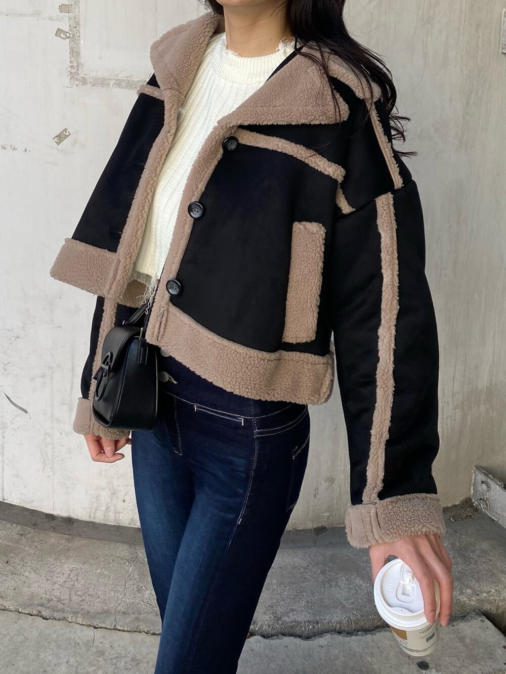 ブルー系のデニムパンツ、ブラック系のムートンコート、ホワイト系のニット/セーターを着用したレディースの秋コーディネートの8枚目の写真