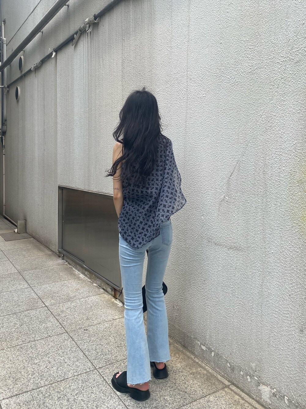 ブルー系のデニムパンツ、ブラック系のハンドバッグ、ブラック系のサンダルを着用したレディースの夏コーディネートの4枚目の写真