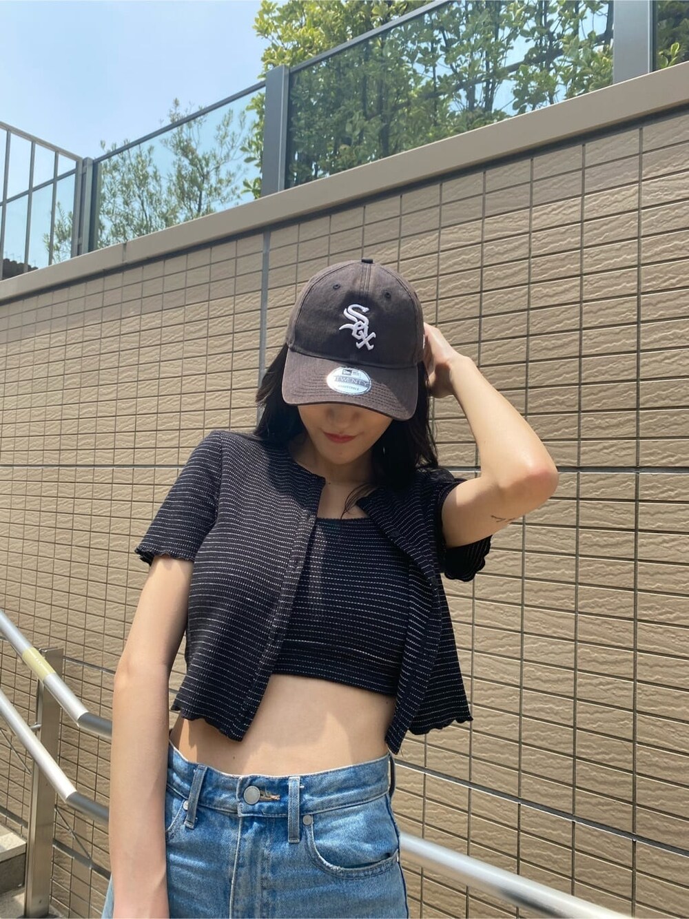 ブラック系のサンダル、ブルー系のデニムパンツ、その他のアンサンブルを着用したレディースの夏コーディネートの5枚目の写真