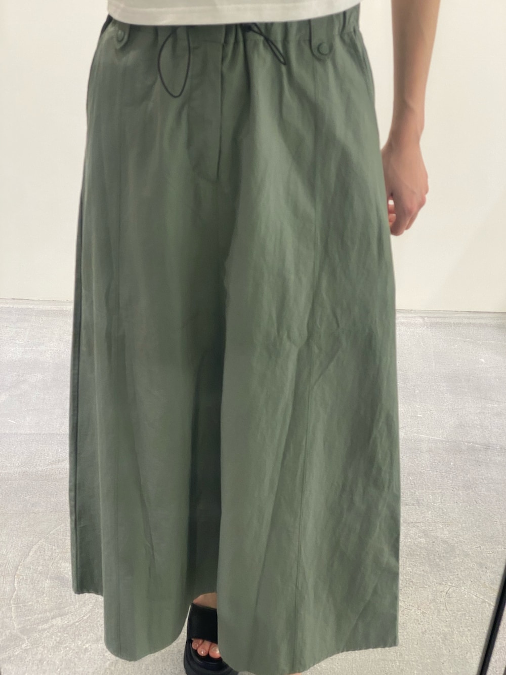 グリーン系のスカート、ブラック系のTシャツ/カットソー、ブラック系のサンダルを着用したレディースの夏コーディネートの7枚目の写真